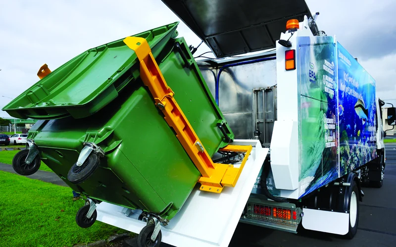 Mobile bin-washing vehicle with a bin raised for cleaning